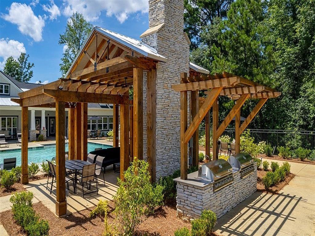 a backyard with a stone fireplace and a wooden pergola