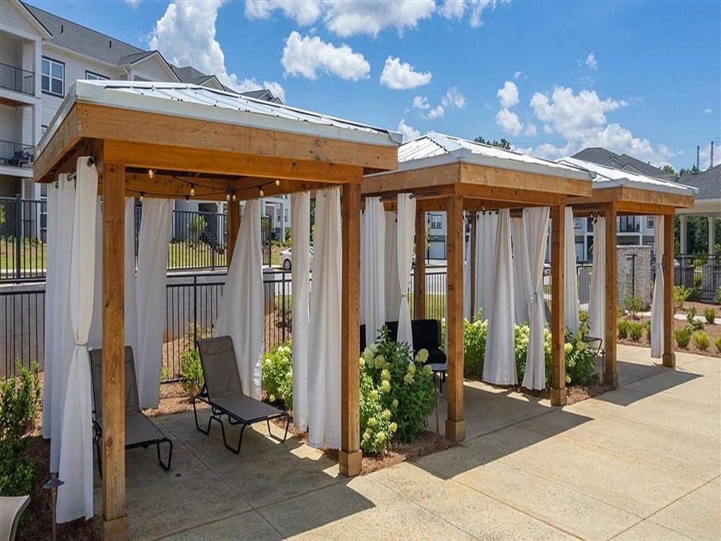 a covered patio with chairs and curtains