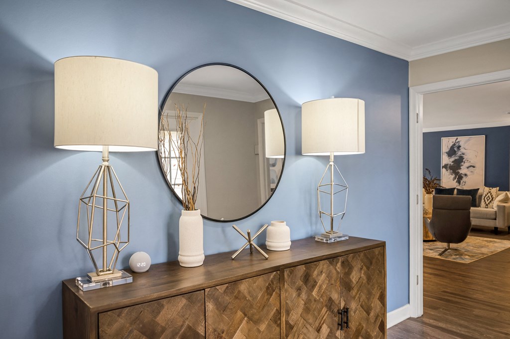 a blue walled living room with a mirror and a dresser with two lamps