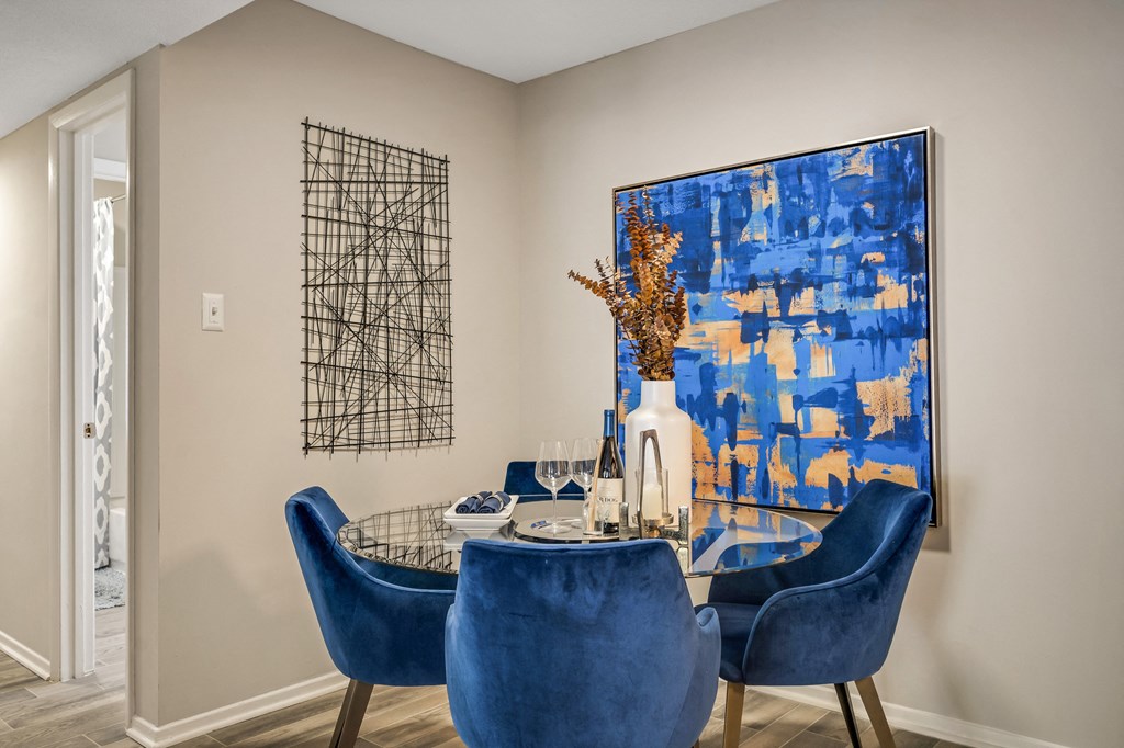 a dining room table with blue chairs and a blue painting on the wall