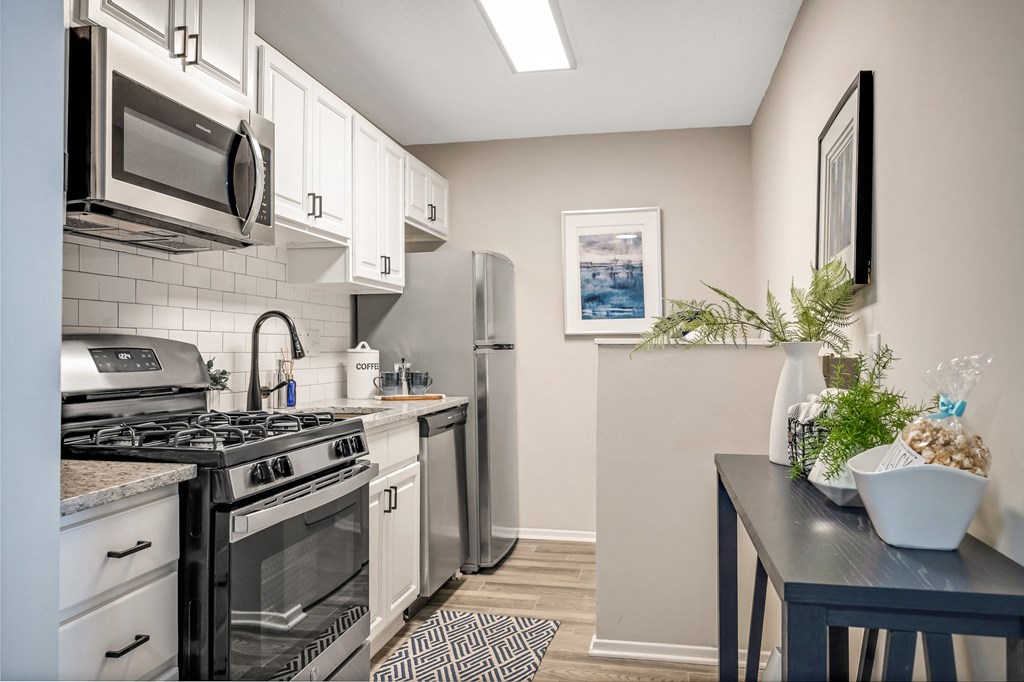 an apartment kitchen with stainless steel appliances and white cabinets