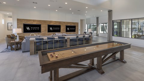 A shiny wooden table is in the middle of a room with a white wall and a row of chairs.