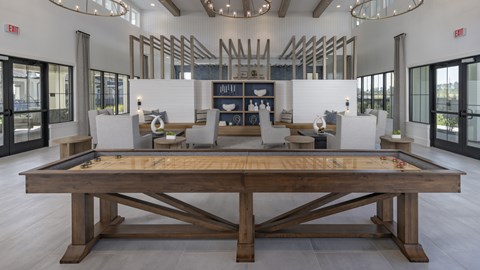 A billiard table is in the middle of a room with a white ceiling and wooden floors.