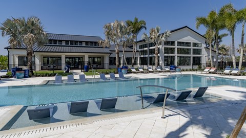 A large swimming pool with lounge chairs and a building in the background.