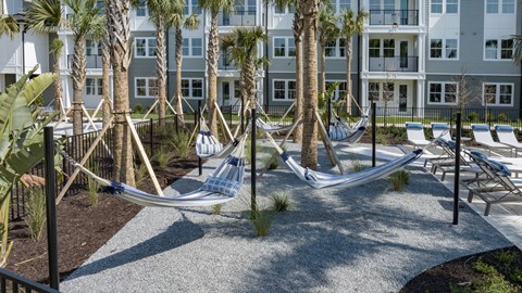 A hammock is strung between two trees in a courtyard.