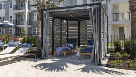 A patio area with a canopy and lounge chairs.