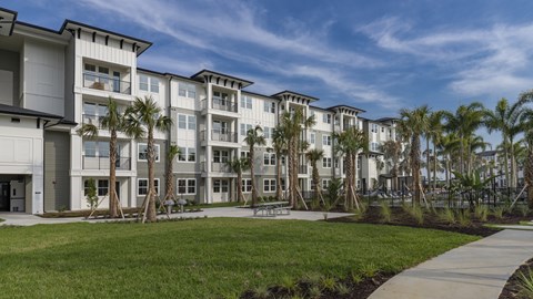 A row of modern apartment buildings with palm trees in front.