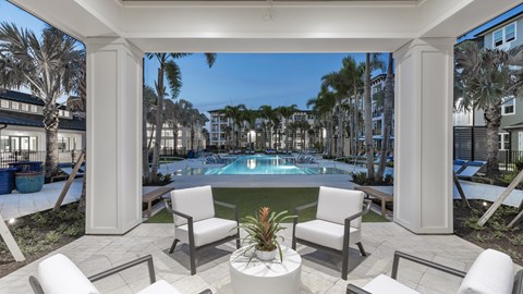 A pool surrounded by white chairs and columns.