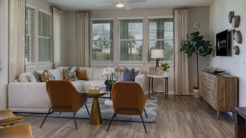 A living room with a white couch, a coffee table, and a large window.
