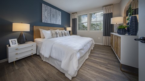 A bedroom with a large bed and a wooden nightstand.
