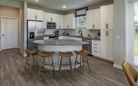 A kitchen with a white island and wooden bar stools.