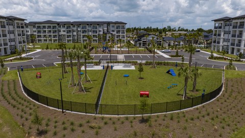 A playground area with a black fence and a red slide is surrounded by apartment buildings.