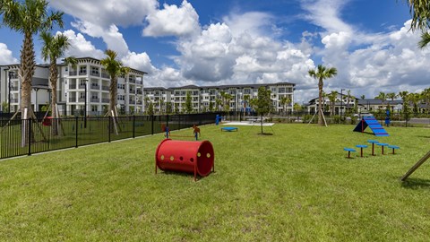 A playground with a red barrel and blue benches in front of a building.