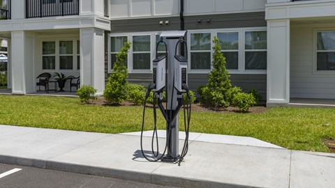 A black electric vehicle charging station is in front of a building.