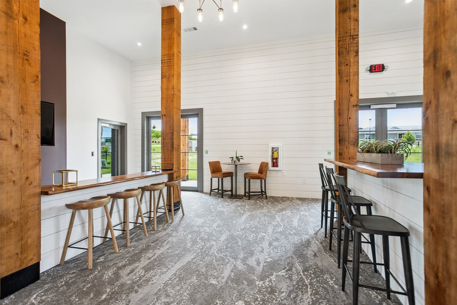 a bar and seating area in a room with white walls and wood beams