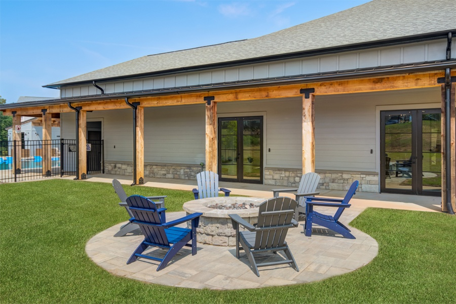 a patio with chairs and a fire pit in front of a house