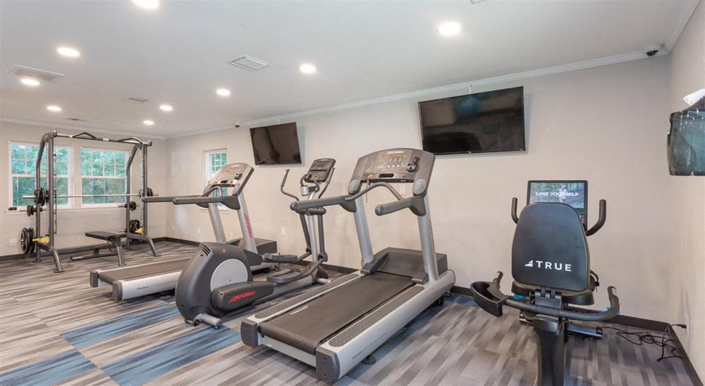 a gym with cardio machines and a tv on the wall