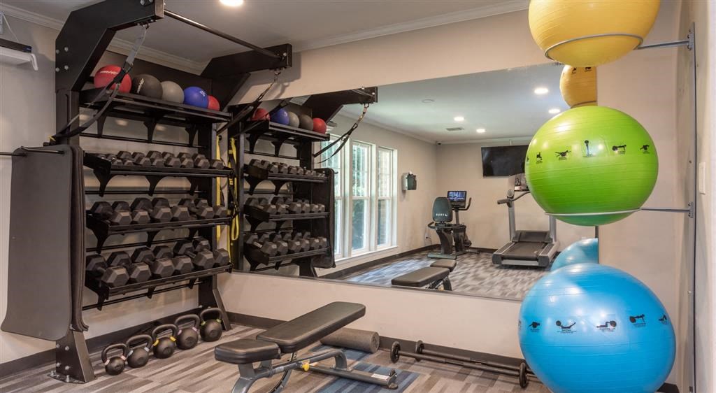 a fitness room with weights and balls and a mirror