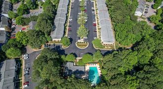 an aerial view of a parking lot with a pool and trees