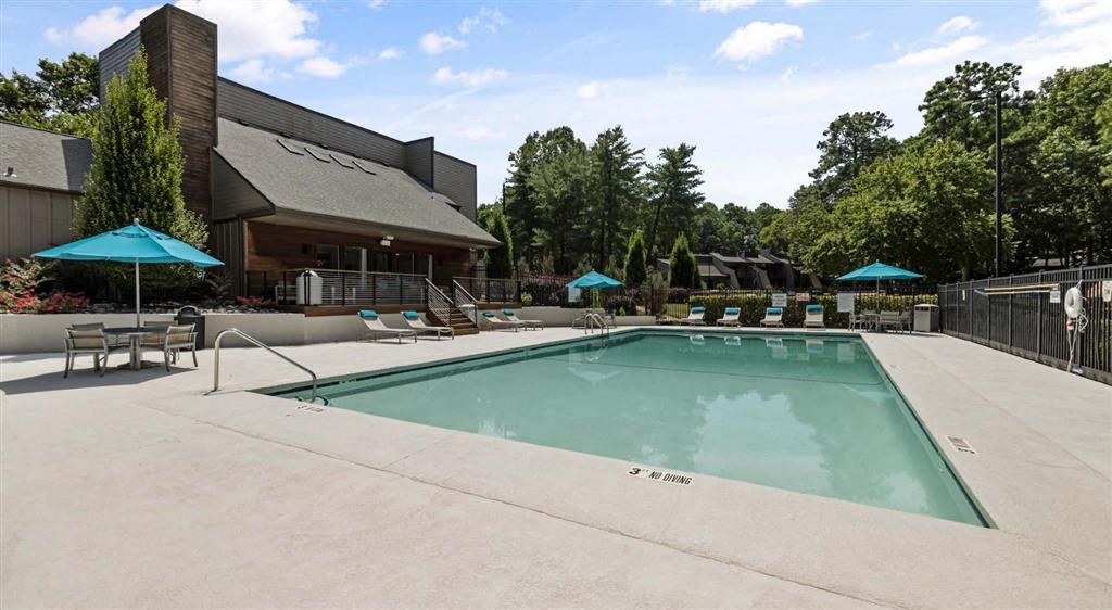a swimming pool with chairs and umbrellas in front of a building