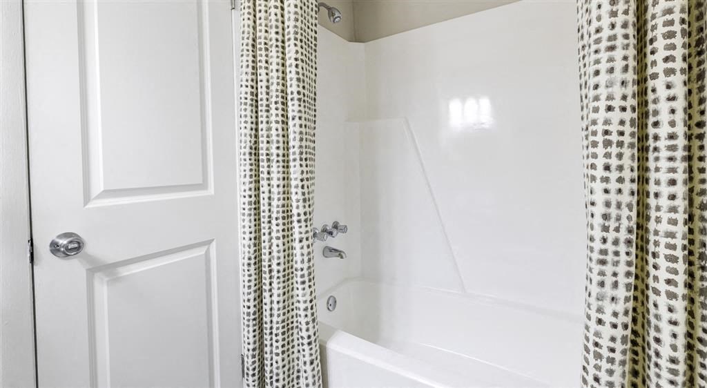 a white bathroom with a shower curtain and a bath tub