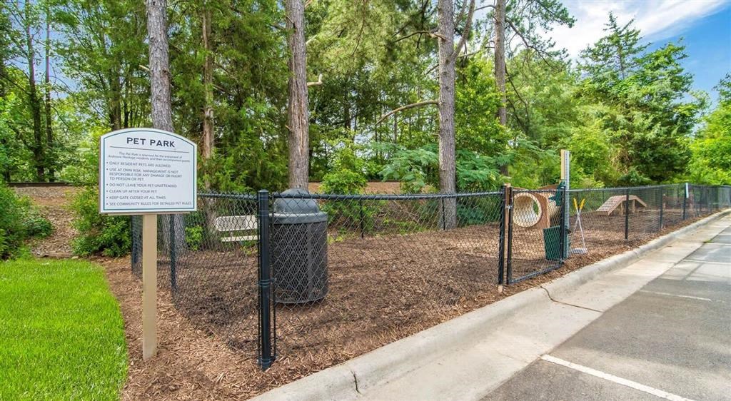 a park with a fence and a sign next to a sidewalk