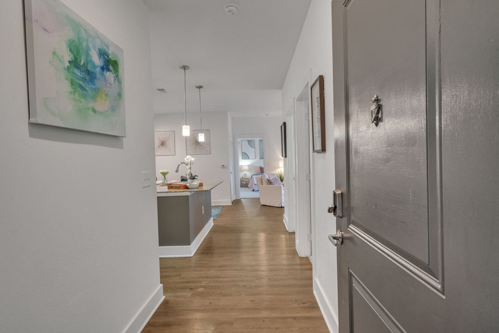 a long hallway with a door to a living room and a kitchen