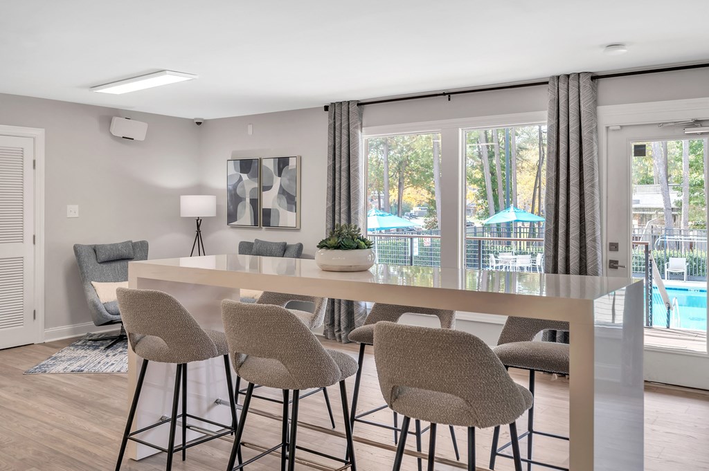 a dining area with a table and chairs and a view of a pool