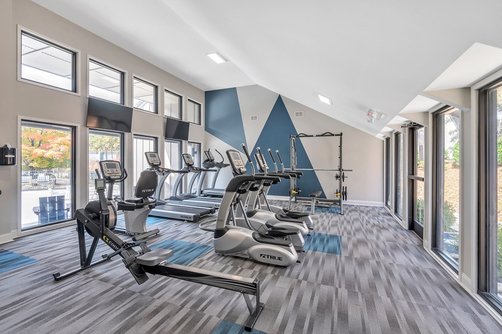 a gym with cardio machines and windows on the wall