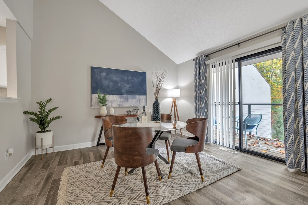 a dining room with a table and chairs and a sliding glass door to a balcony