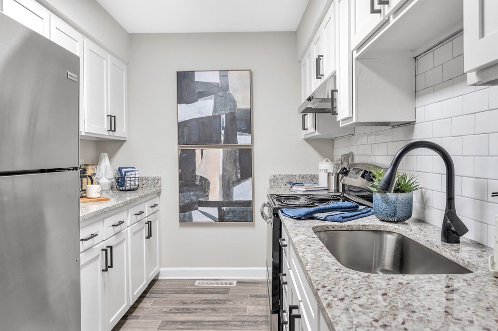 a kitchen with granite counter tops and white cabinets