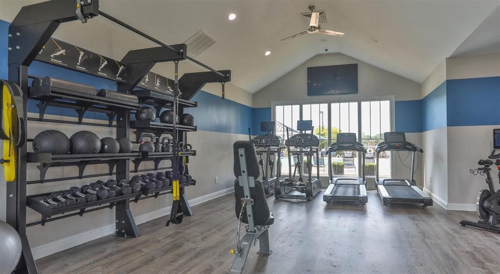 the gym is stocked with weights and cardio equipment in a room with a window