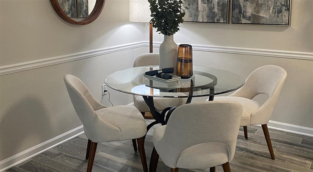 a dining room table with white chairs and a vase