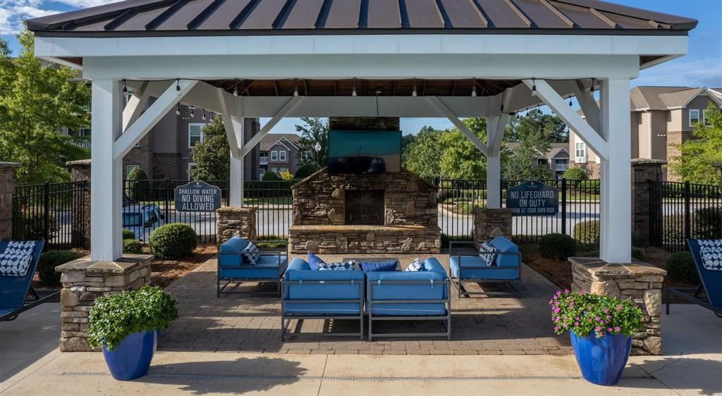 a pavilion with blue couches and a fire pit