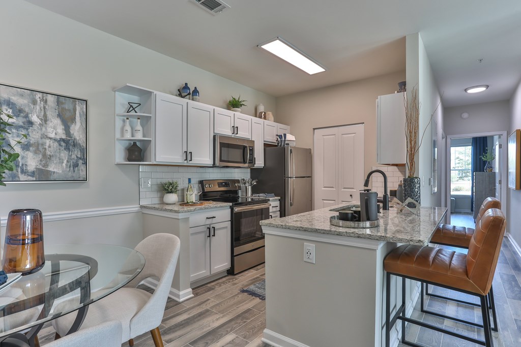 A kitchen with white cabinets and a marble countertop.