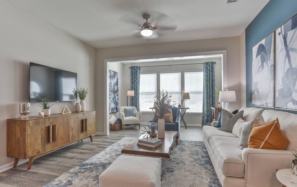 A living room with a white couch, a wooden cabinet, and a ceiling fan.