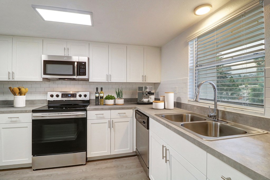 a kitchen with white cabinets and black appliances and a sink
