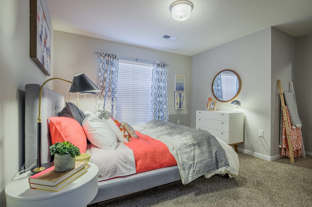 A bedroom with a bed, nightstand, and a window with curtains.
