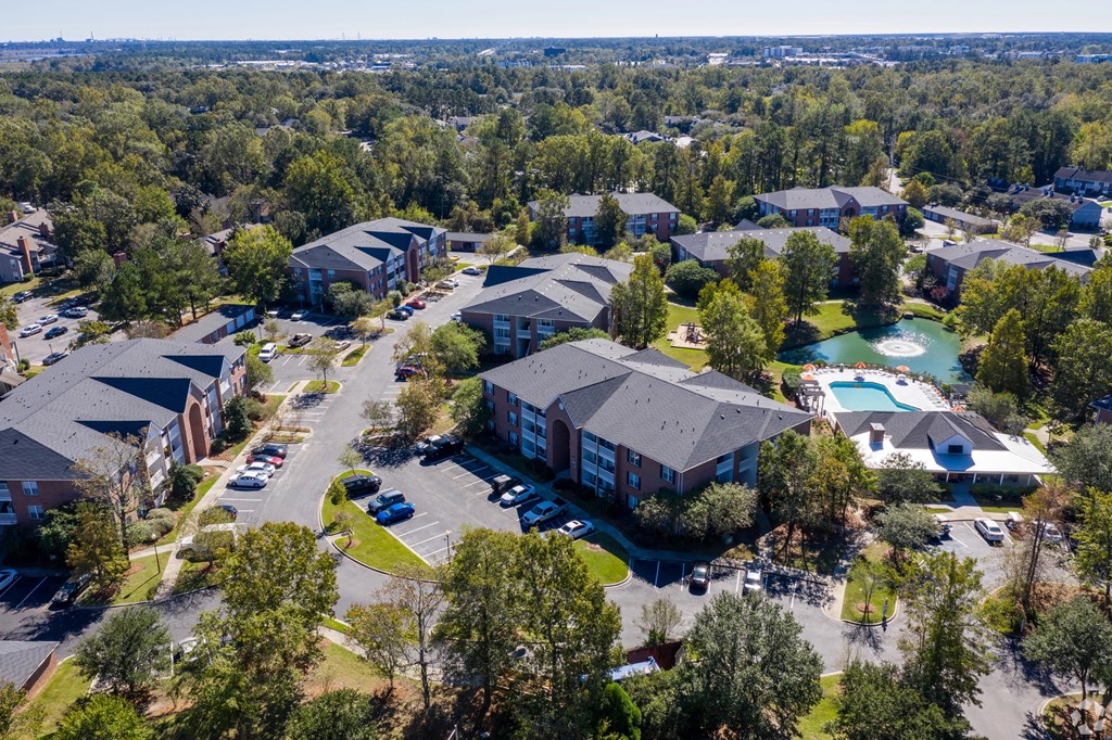 A bird's eye view of a residential area with houses, cars, and a pool.