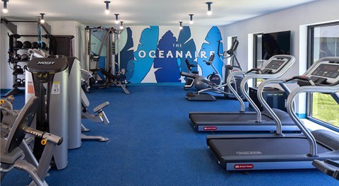 a gym with cardio equipment and a wall with the oceanaris logo