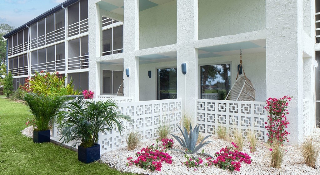 an exterior view of a white building with flowers and plants