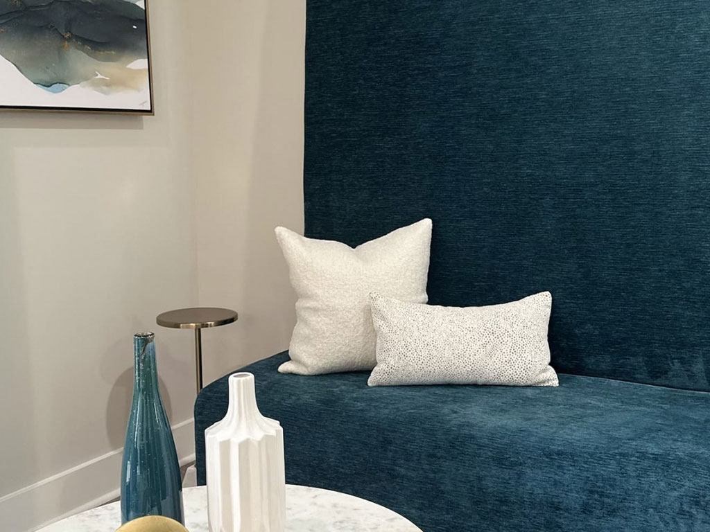 a blue couch with white pillows and a white table
