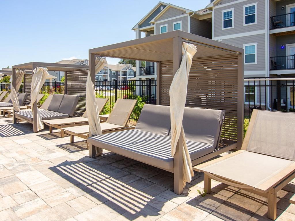 a row of lounge chairs with umbrellas on a patio