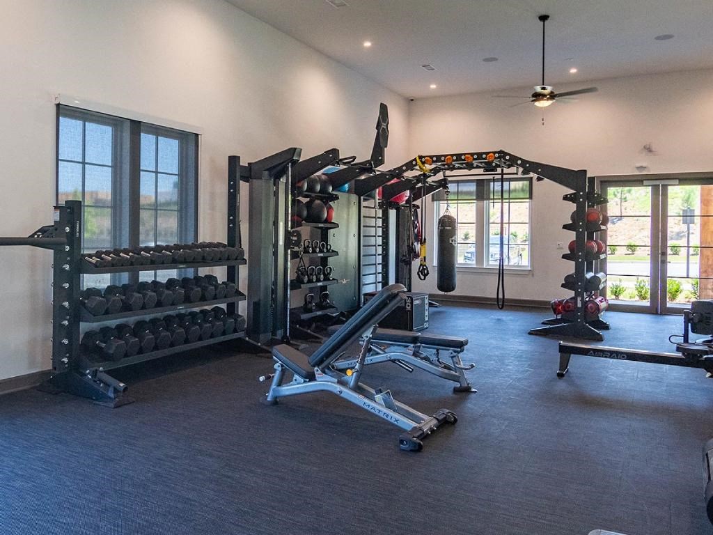 a home gym with a lot of equipment and windows