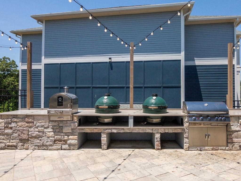 three bbqs in front of a house with a grill
