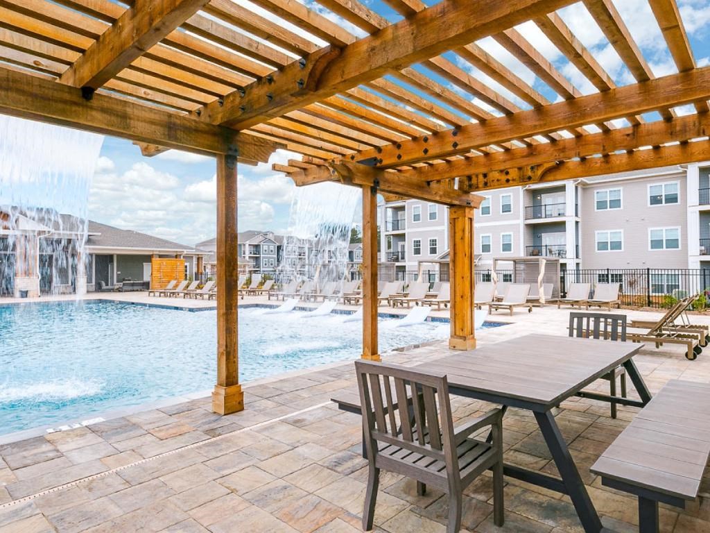a patio with a table and chairs next to a swimming pool