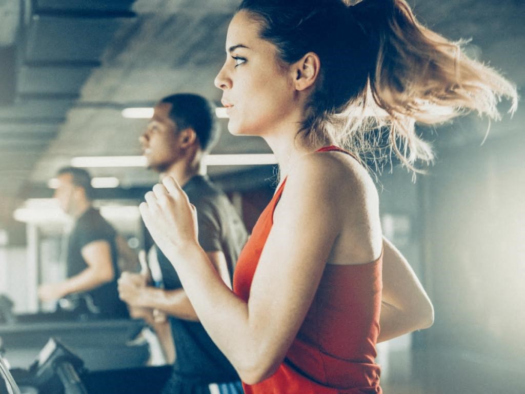 a woman running on a treadmill in a gym