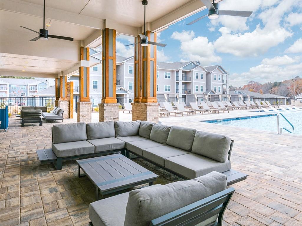 a lounge area with couches and tables next to a swimming pool