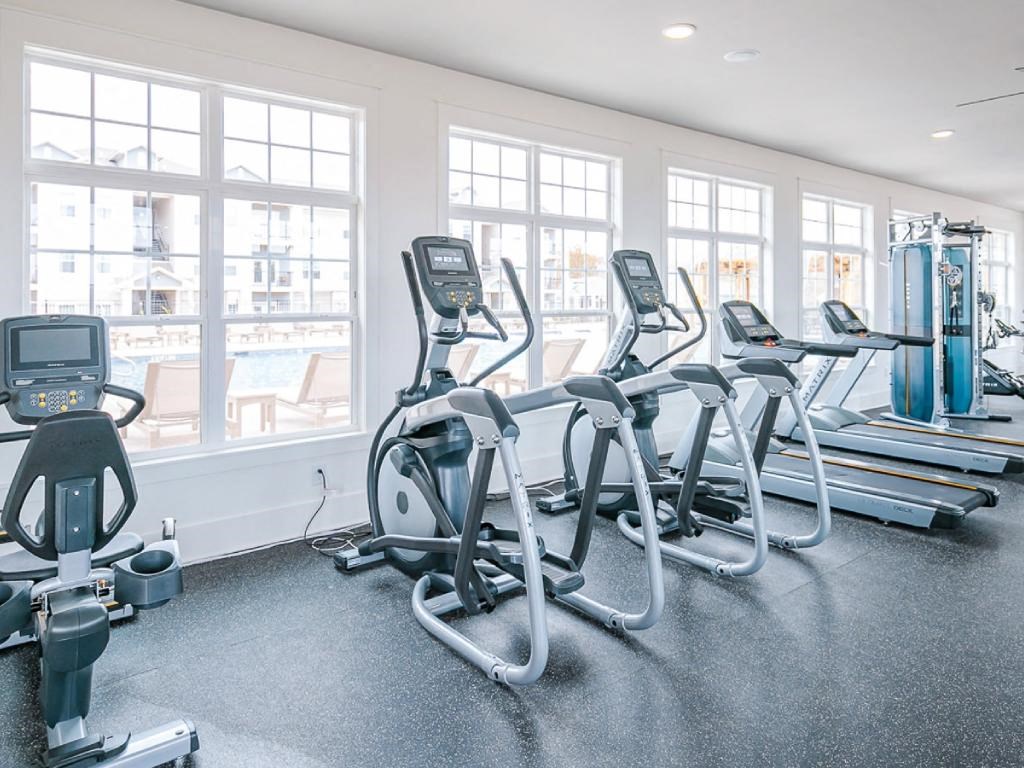 a gym with cardio equipment and windows in a building