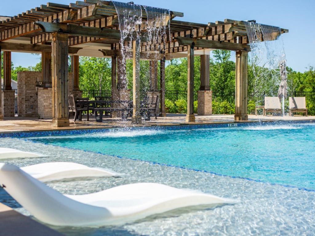 a swimming pool with a water feature and a pergola